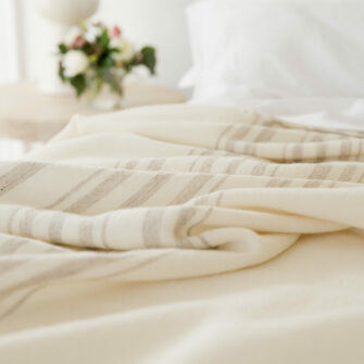 A detail of Swans Island's classic Grace blanket, handwoven with undyed natural wool with a traditional striped border in undyed grey.