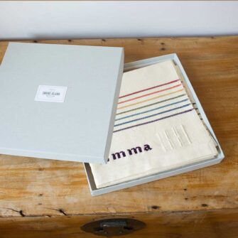Swans Island Company's Rainbow Borders Baby Blanket is shown here in a signature grey linen gift box.
