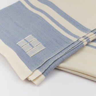Casa Branca x Swans Island - Branca Grande Throw . 100% soft merino wool with hand-dyed stripes and ivory silk binding. Handwoven in Maine. Shown here in Sky Blue.