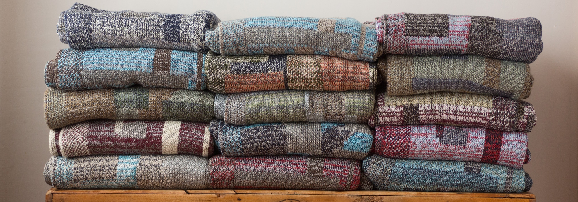 Swans Island Company's Artisanal Patchwork Knit Throws 2026 Drop #2 - A stack of folded one-of-a-kind knit throws.