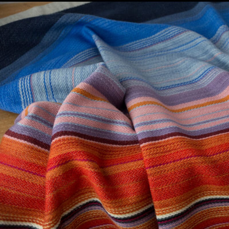 Swans Island Company's Horizon Limited Edition 2026 Throw - A tangible homage to the vibrant colors of first light and golden hour when the sun rises and sets. Handwoven in Maine with hand-dyed wools - a textiles collectors piece. A closeup detail of the transition from water to sky.
