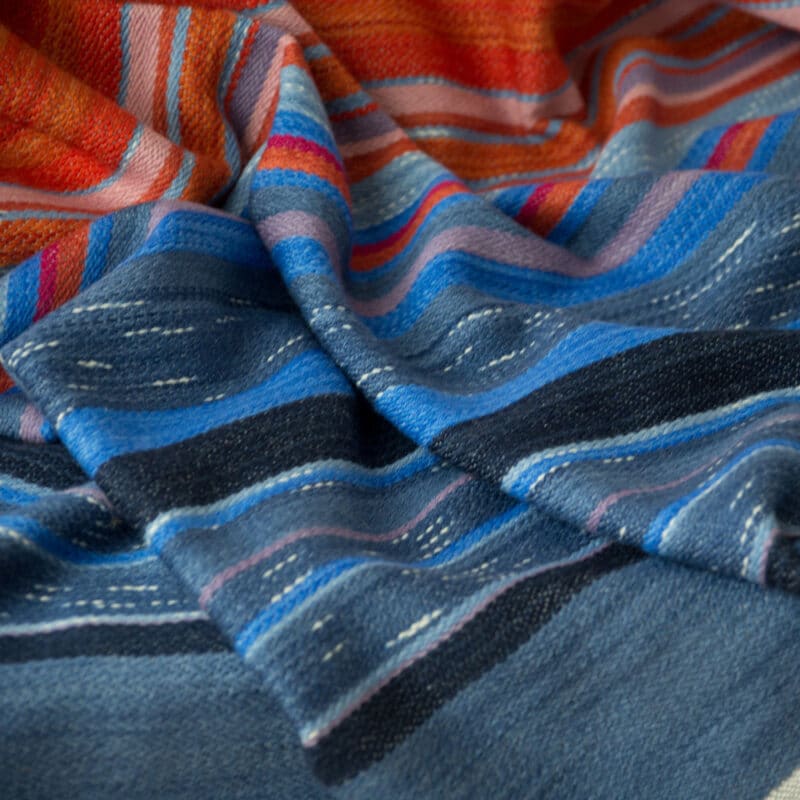 Swans Island Company's Horizon Limited Edition 2026 Throw - A tangible homage to the vibrant colors of first light and golden hour when the sun rises and sets. Handwoven in Maine with hand-dyed wools - a textiles collectors piece. A closeup detail of the shades of watery blues.