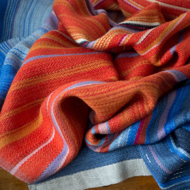 Swans Island Company's Horizon Limited Edition 2026 Throw - A tangible homage to the vibrant colors of first light and golden hour when the sun rises and sets. Handwoven in Maine with hand-dyed wools - a textiles collectors piece. A closeup detail of the transition from water to sky.