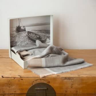 Swans Island Company's Gossamer Alpaca Shawl is whisper thin baby alpaca in undyed natural colors. Shown here in grey with camel and ivory band in signature gift box.