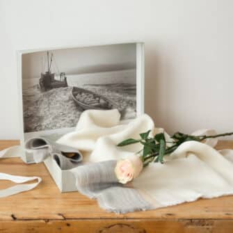 Swans Island Company's Gossamer Alpaca Wrap is whisper thin baby alpaca in undyed natural colors. Ivory with light beige and light grey band swatch. In signature gift box with one pink rose.